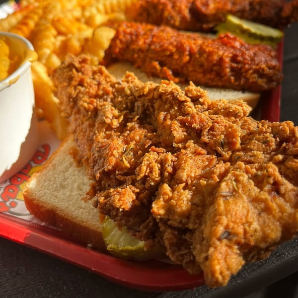 Crispy fried chicken tenders on white bread with pickles, crinkle-cut fries, and dipping sauce.