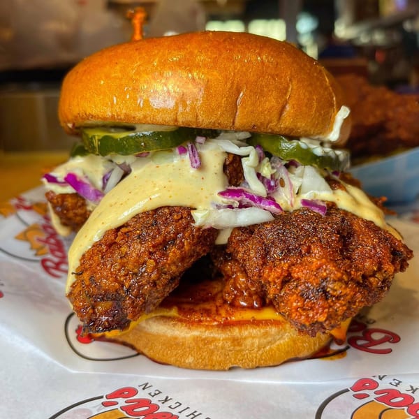 Baba's Hot Chicken sandwich with crispy fried chicken, coleslaw, pickles, and sauce on a bun.